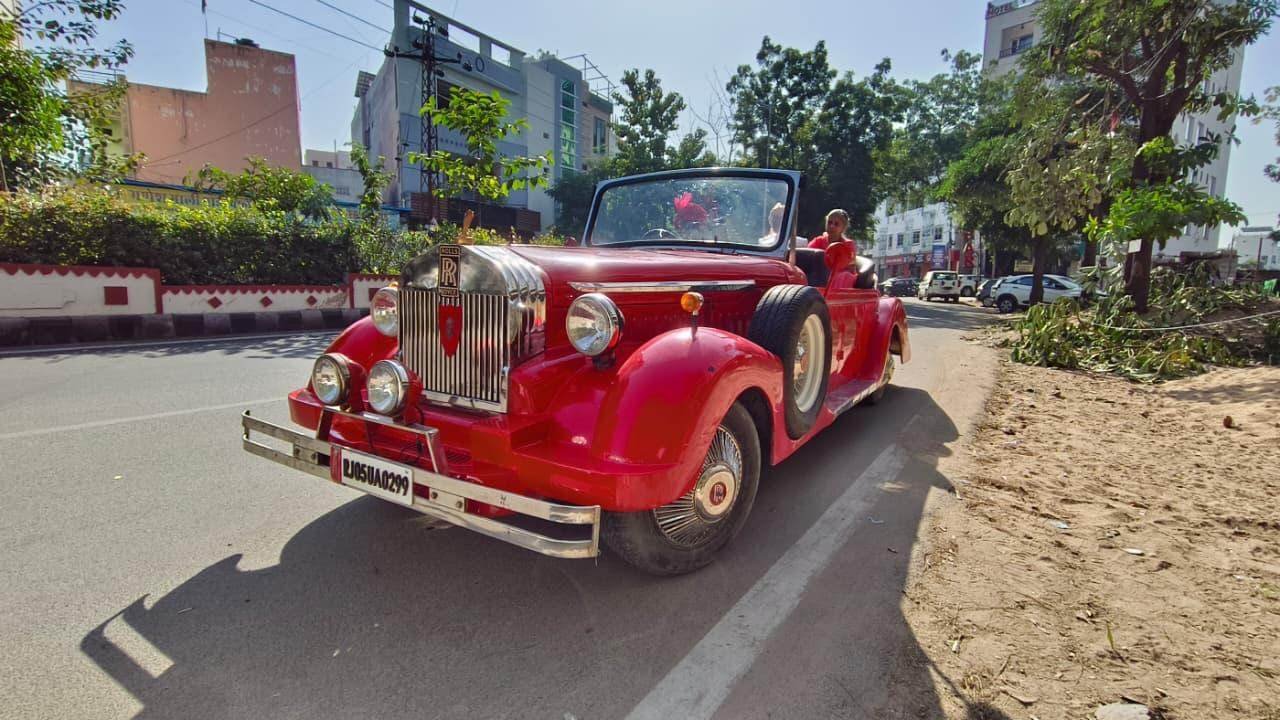 Red Rolls-Royce style vintage car on the road, available for processions and weddings in Udaipur