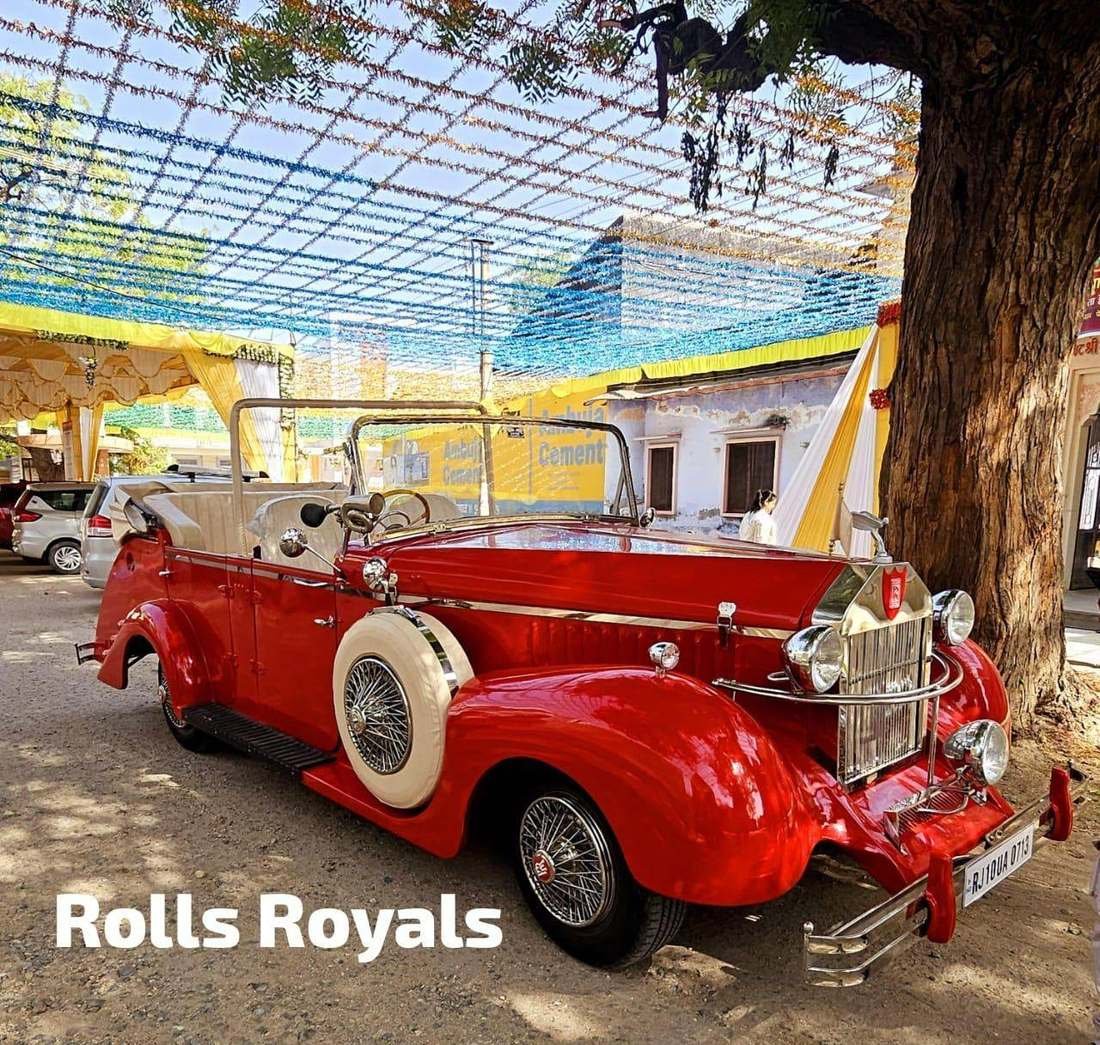 Red Rolls-Royce style vintage wedding car at a decorated venue in Udaipur