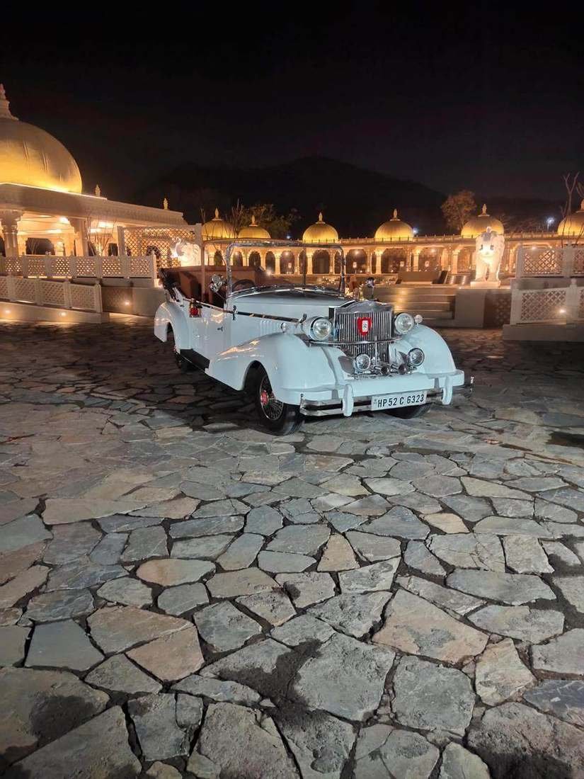 White Rolls-Royce style vintage car lit up at a palace-style venue in Udaipur at night